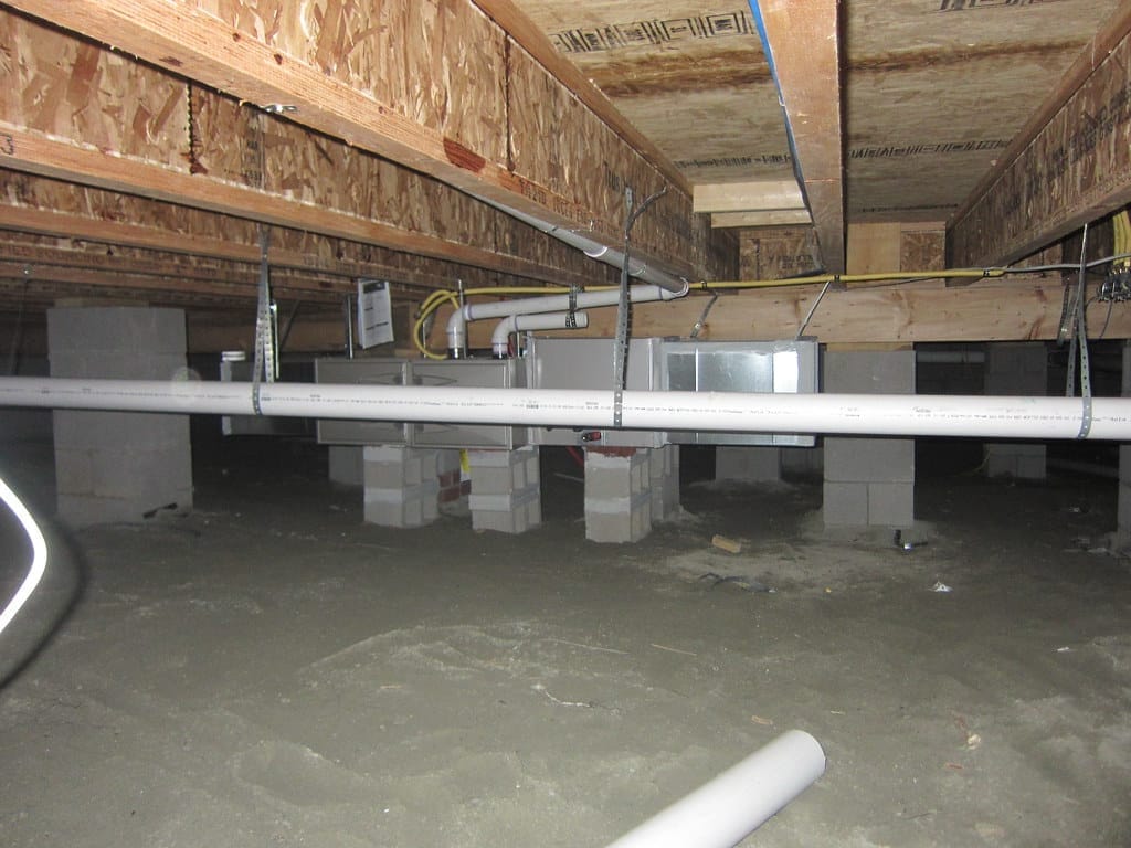 A Wilmington-area crawl space of the type we encapsulate — block piers, joists, and a dirt floor