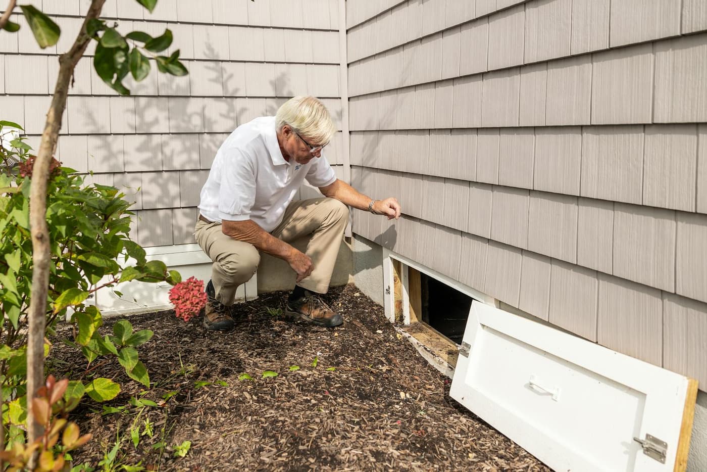 A home inspector examining the crawl space access door of a Wilmington-area home